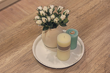 Candles and roses in a vase on a wooden table. Interior