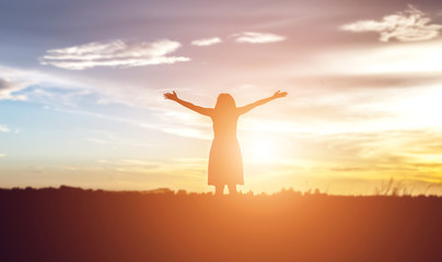 Silhouette of woman praying over beautiful sky background