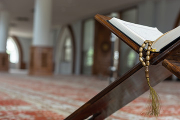 Holy Quran with beads over wooden background closeup. Small shal