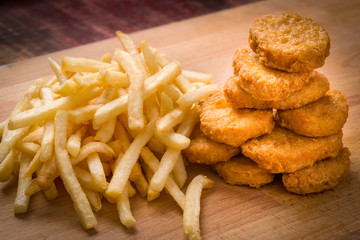 Golden brown Chicken nuggets and French fries on a wood backgrou