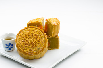 A chinese moon cake with hot tea on white plate