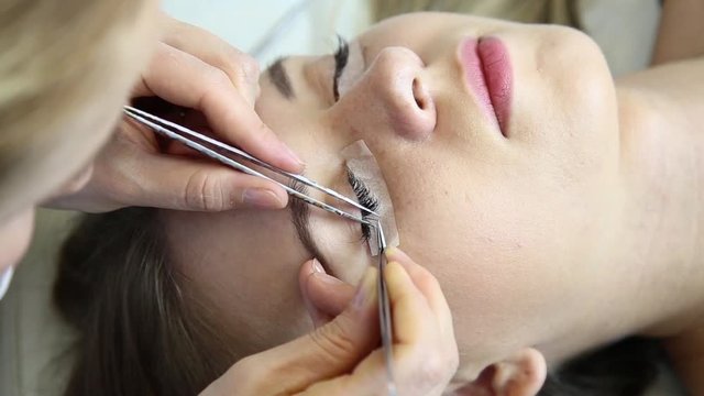 Beautiful young woman with eyelash extension. Woman eye with long eyelashes. Beautician eyelash extension for young woman in a beauty salon