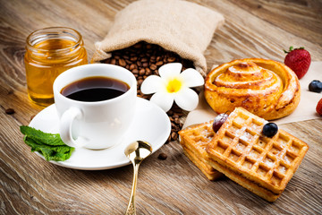 Cup of coffee and pastry on wooden background