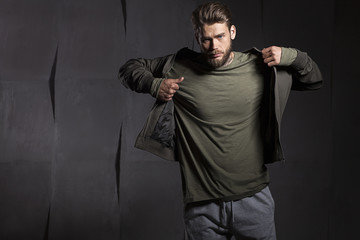 The young man takes off his jacket on gray cement background