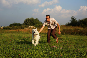 Man playing with white swiss shepherd dog