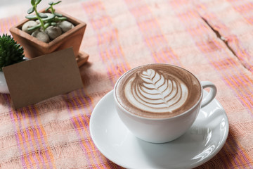 Cup of coffee latte on desk and card.