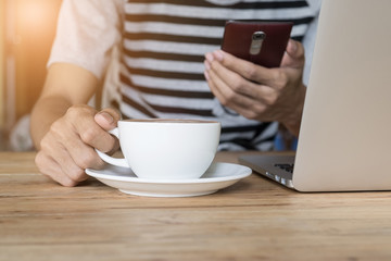 young man working at coffee shop using smart phone and laptop co