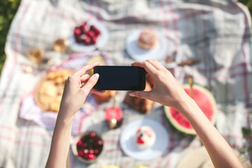 Girl photographing on phone picnic