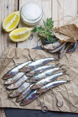 fresh sardines raw fish with coarse salt and thyme on brown pape