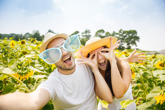 young happy couple man and woman are in a field of sunflowers, make selfie pics