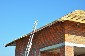 Roofing Construction. Wooden Roof Frame Unfinished House Construction with metal ladder.