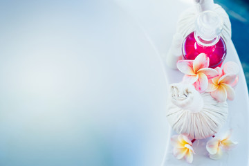 Cosmetic products , frangipani flowers,  herbal and massage stamps on bathtub with blue water. Spa or Wellness background, banner