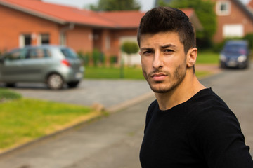 Fototapeta premium Junger Mann vor Hauseinfahrt / Wohnung