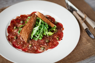 Meat carpaccio of beef on wood table