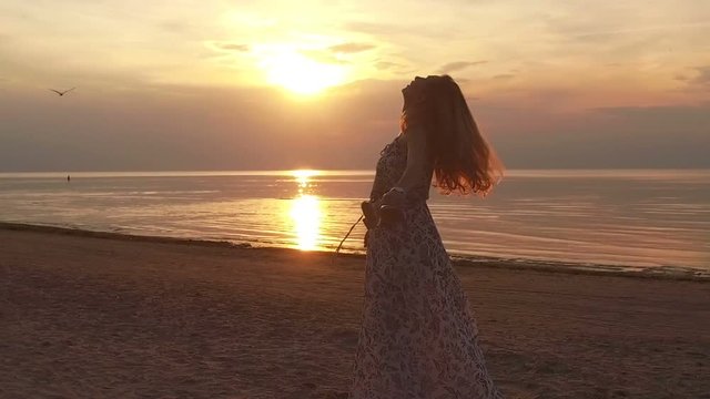 Young woman spinning in Summer beach Sunset