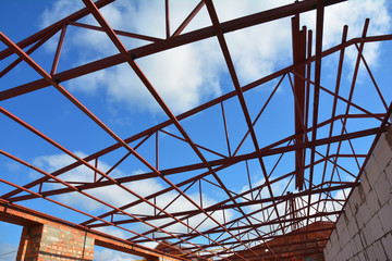 Steel roof trusses details with clouds sky background. Steel roof trusses sitting on concrete pole view from inside home factory.