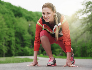 Attractive blonde woman running on track outdoors.