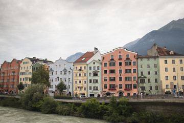 Fototapeta na wymiar Typical Austrian houses at the embankment of the Inn river in Innsbruck, Austria with the Alps in the background 
