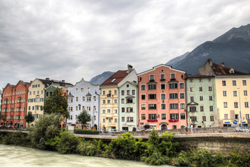 Naklejka na ściany i meble Typical Austrian houses at the embankment of the Inn river in Innsbruck, Austria with the Alps in the background 