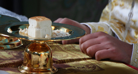 Hands of priest consecrates bread during orthodox liturgy ceremony