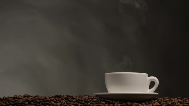 Cup of coffee with steam. Dark background with coffee beans