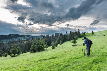 Photographer shoots a mountain landscape in the evening