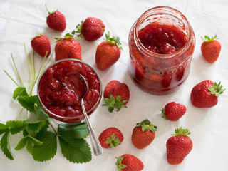 Strawberry jam in a glass bowl, berry and leaf isolated on white background