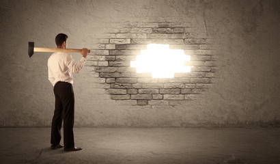 Business man hitting brick wall with hammer and opening a hole