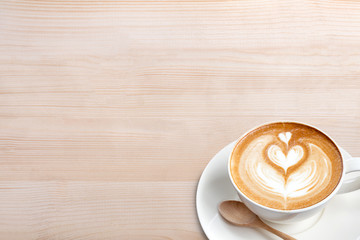 A cup of coffee latte with spoon on wood table
