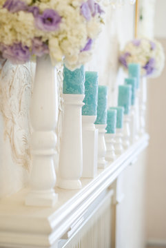 Floral arrangement with white and blue flowers and candles on candle holders. Wedding decor idea. 