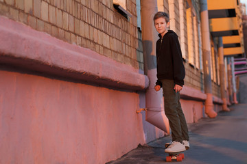 Skateboarding teenager riding right on sunset city street