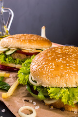 Two Burger with fries, sauce and condiments on the table.