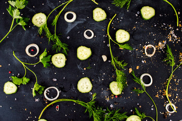 Rings of onion, herbs, spices scattered on a dark background. Flat lay.