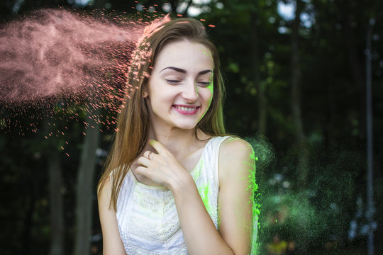 Happy brunette woman playing with colored powder