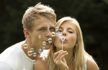 TEENAGERS BLOWING BUBBLES - A teenage girl and boy blowing bubbles 