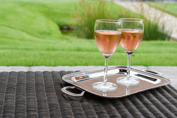 Two glasses of rose wine on silver serving tray.
