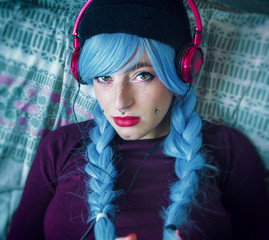 Chica alternativa con el pelo azul escuchando música con unos cascos