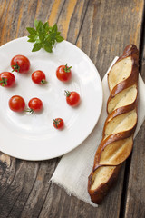Cherry tomatoes with fresh basil and a bread bun on a wooden table, copy space, vertical, vibrant   