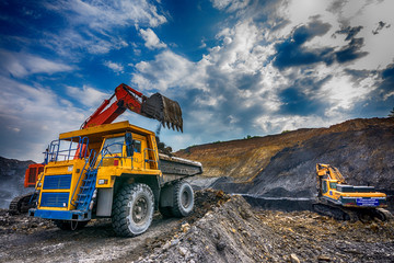 NOVOKUZNETSK, RUSSIA - JULY 26, 2016: Big yellow mining truck and excavator at worksite
