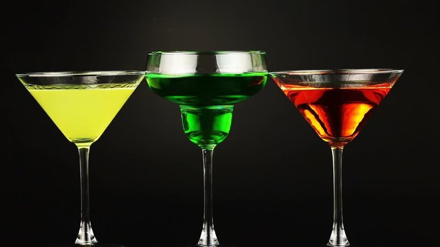 Yellow, green and orange cocktail into glasses on pink background