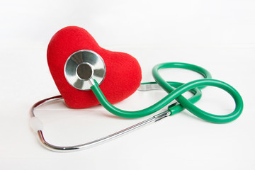 Green stethoscope in doctor hand and red heart