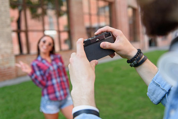 Guy photographing his girlfriend outdoors