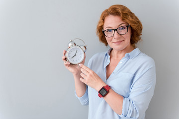 Positive woman holding alarm clock.