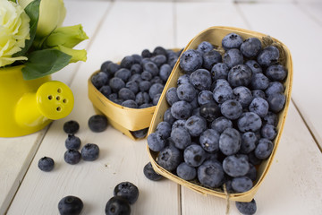 fresh berries in a basket on a table with a bouquet of flowers