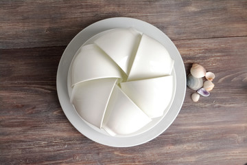 White china porcelain on a wooden table with sea shells composition detail. Six cups stacked. Special light. Top view.