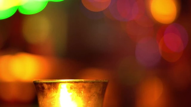 Candle in a glass stay on wooden table in blues music bar. Blurred backround. Bokeh. Colored illumination. 4K
