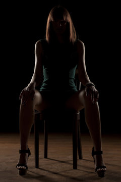 woman sitting on a chair in the dark with wide open legs