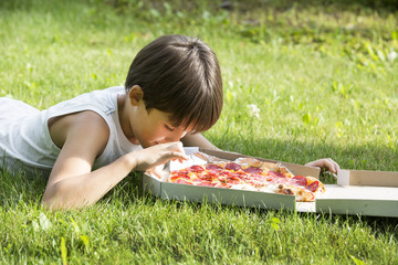 boy eating pizza on the nature
