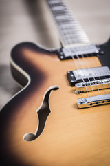 Semi hollow jazz body electric guitar close up on a sunburst orange color and bright chrome electronics