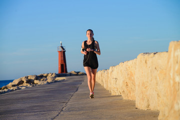 Young sporty girl running alone at beautiful sunset near the lig